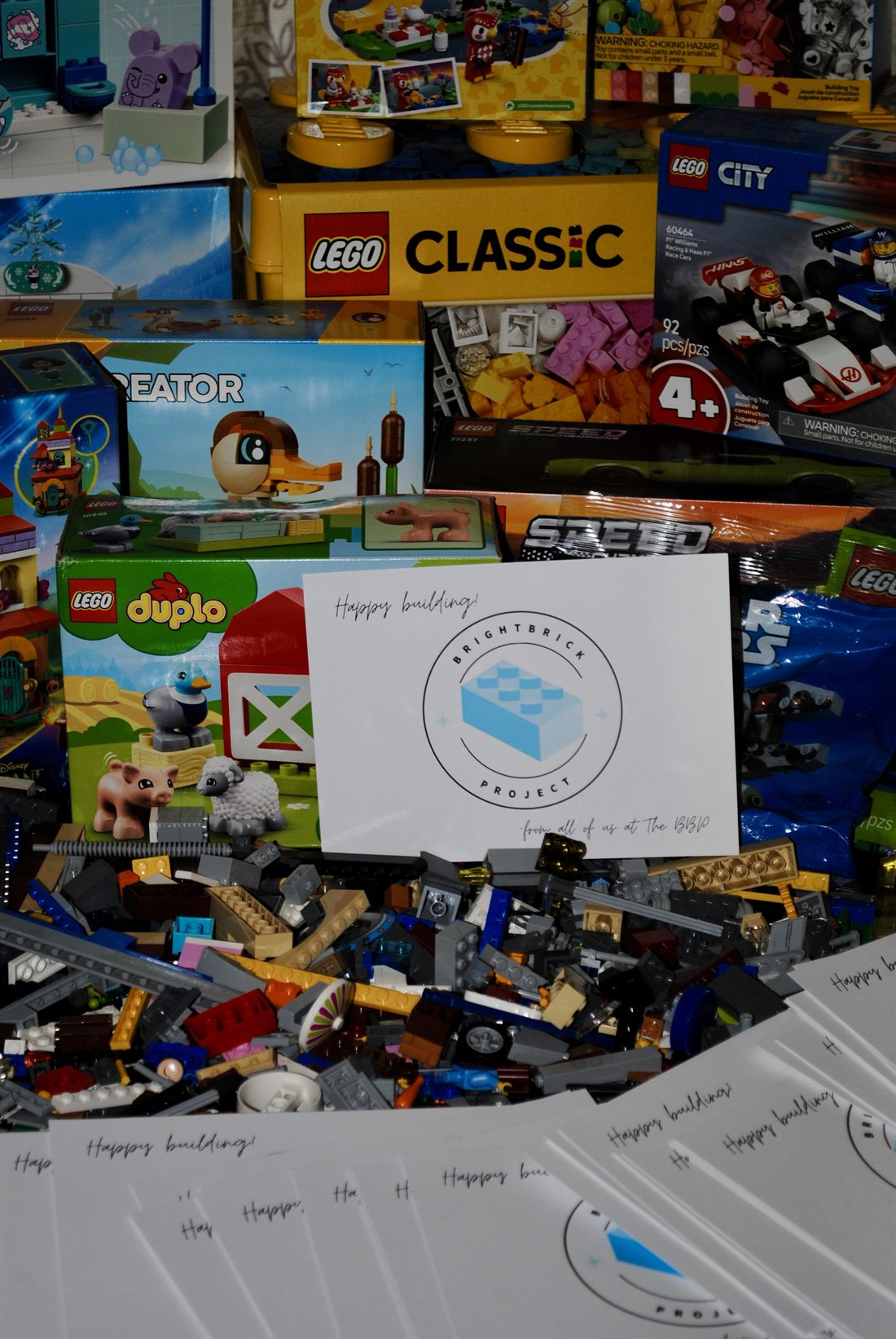 Donated LEGO sets and a bin of loose bricks with a BrightBrick 'Happy building' card, ready to be gifted.